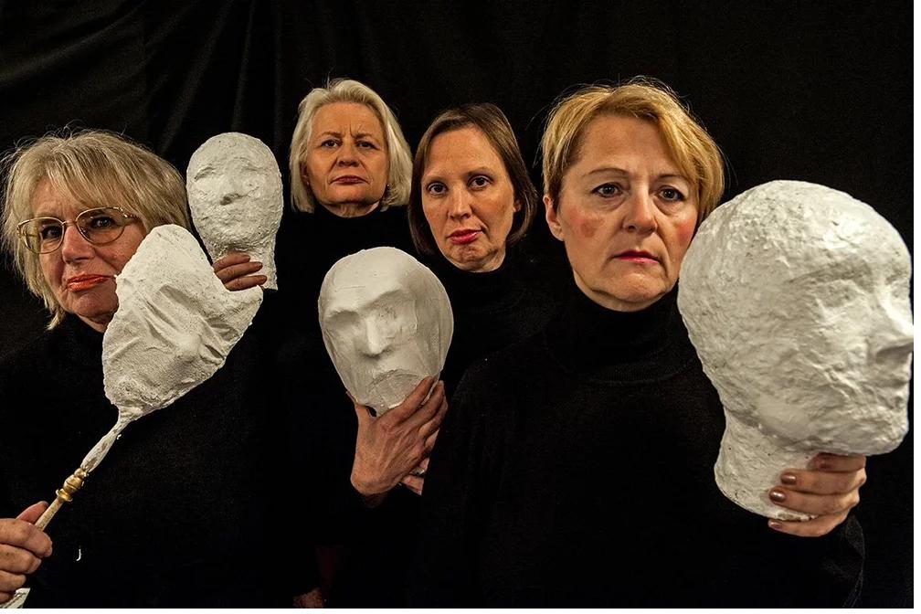 Four performers of the play “Roter Rosen Regen” holding white plaster masks in front of them