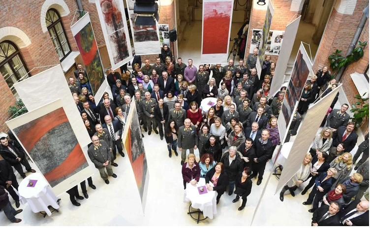 View from above into the hall of the Rossauer barracks with many guests between large art prints